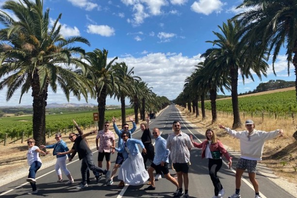 a group of people walking down a street next to a palm tree