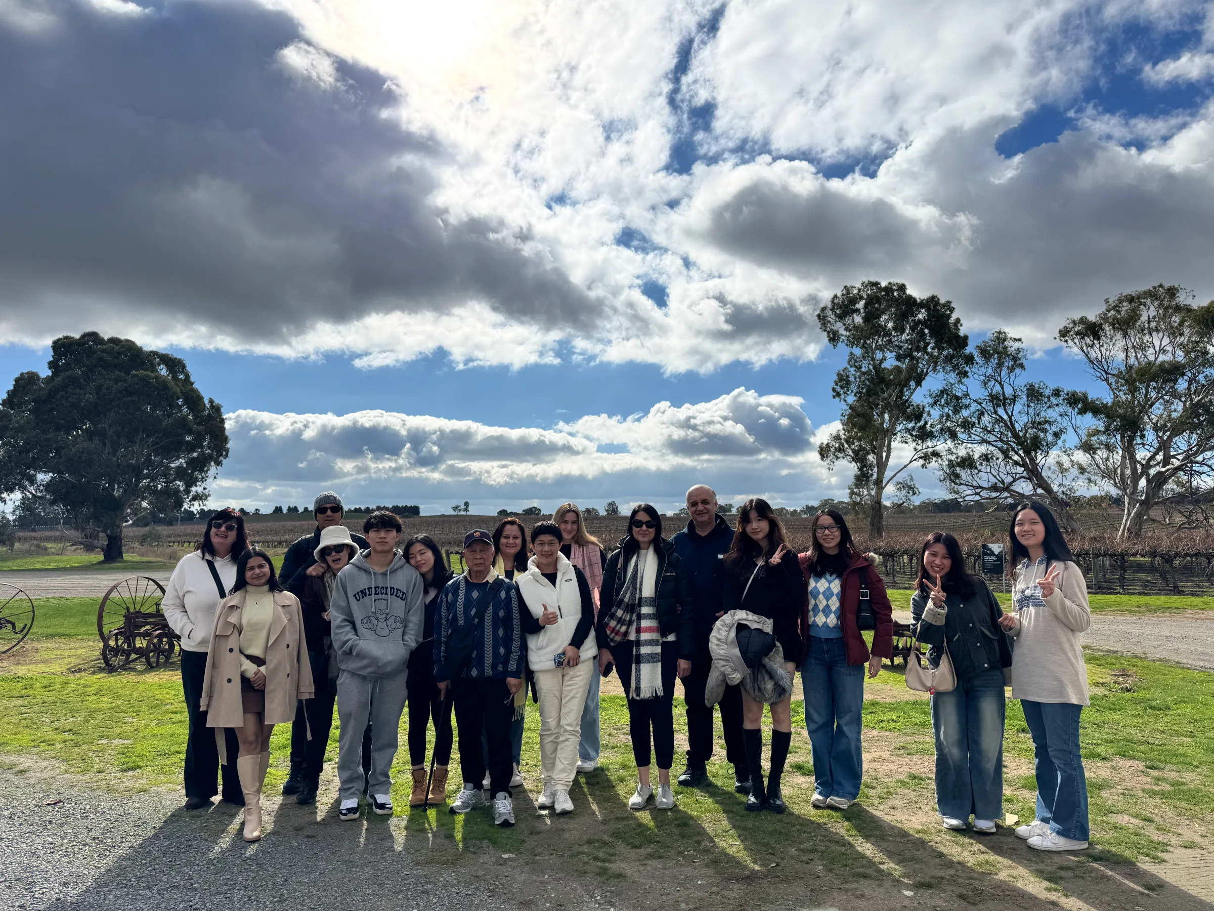 Group of people posing outside with trees and cloudy sky in the background.