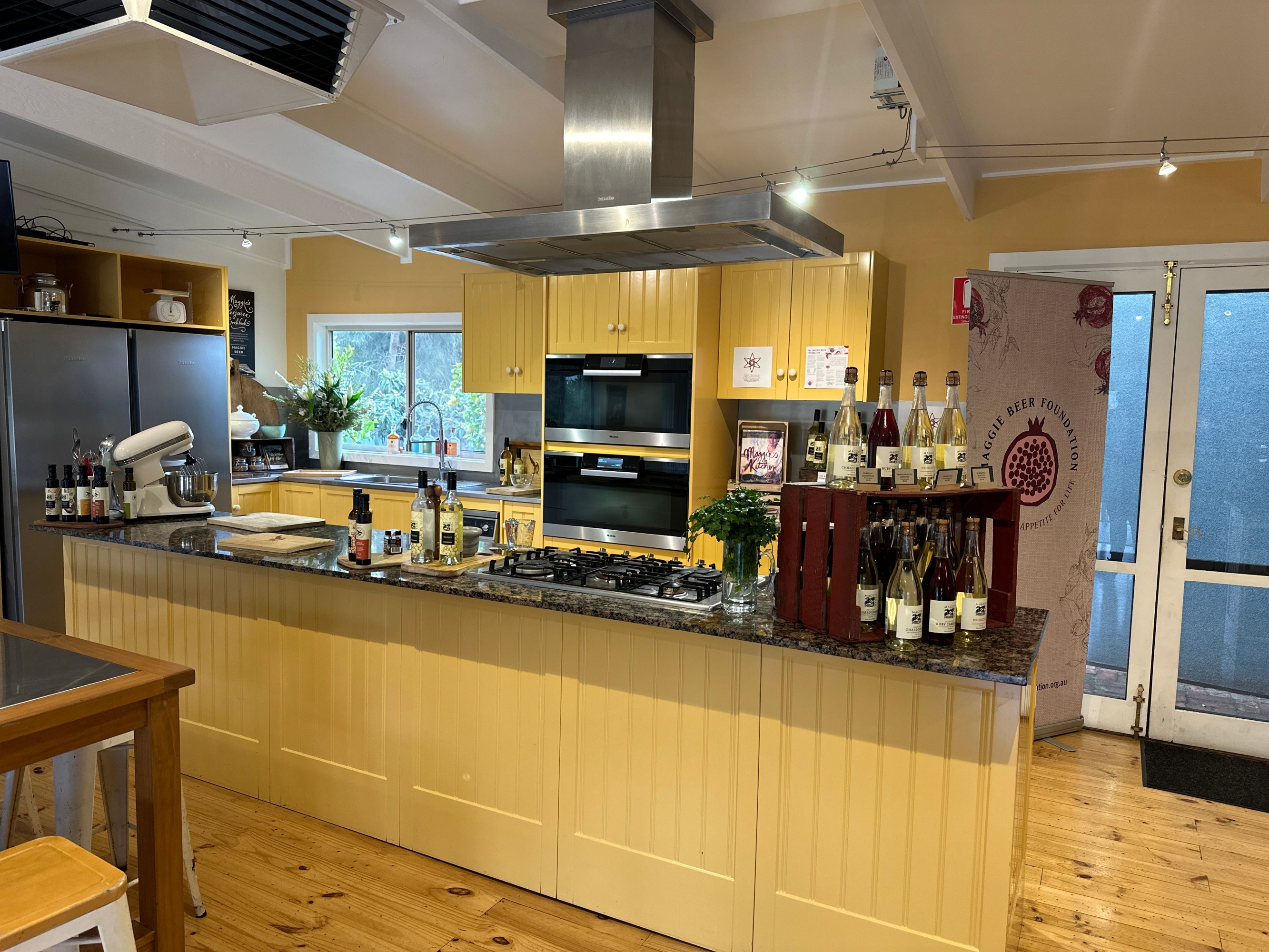 Spacious kitchen with yellow cabinets, kitchen island, appliances, and bottles displayed.