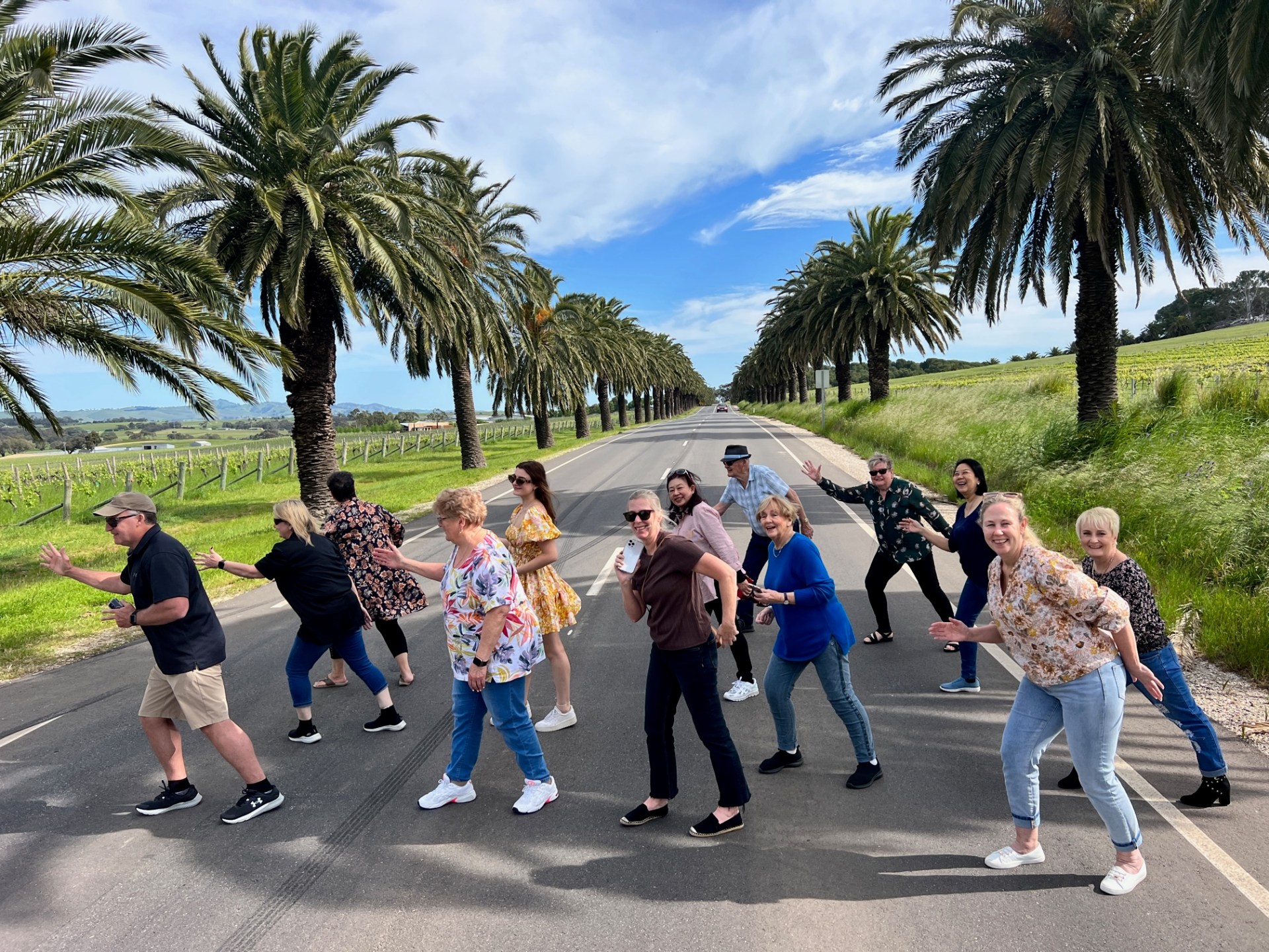a group of people walking down a street next to a palm tree