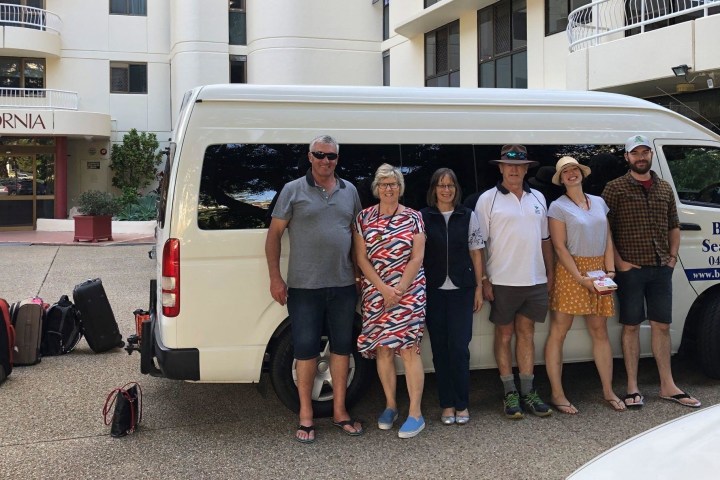 a group of people standing in front of a car posing for the camera