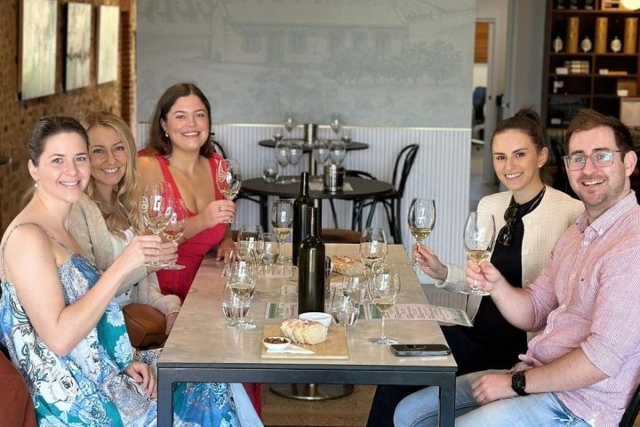 Group of five people sitting at a table enjoying wine in a modern dining area.