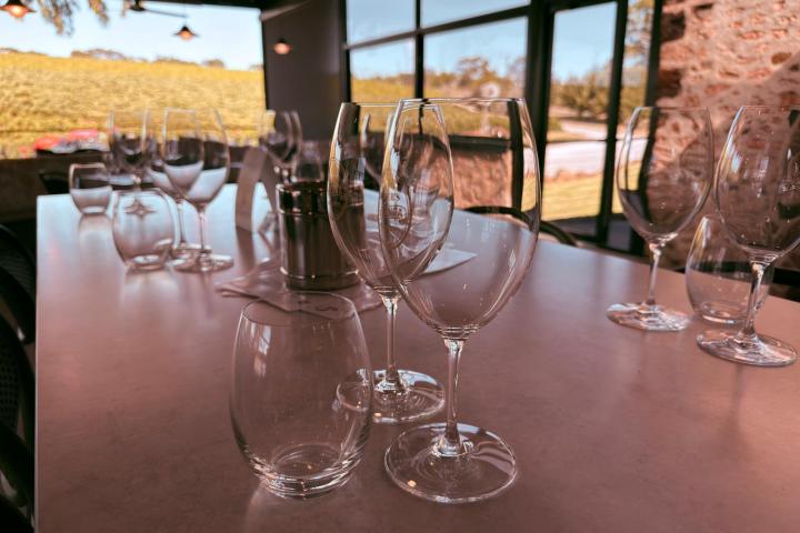 Empty wine glasses on a table near large windows with outdoor view.