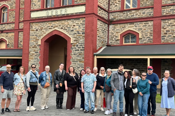 Group of people smiling in front of a historic brick and stone building.