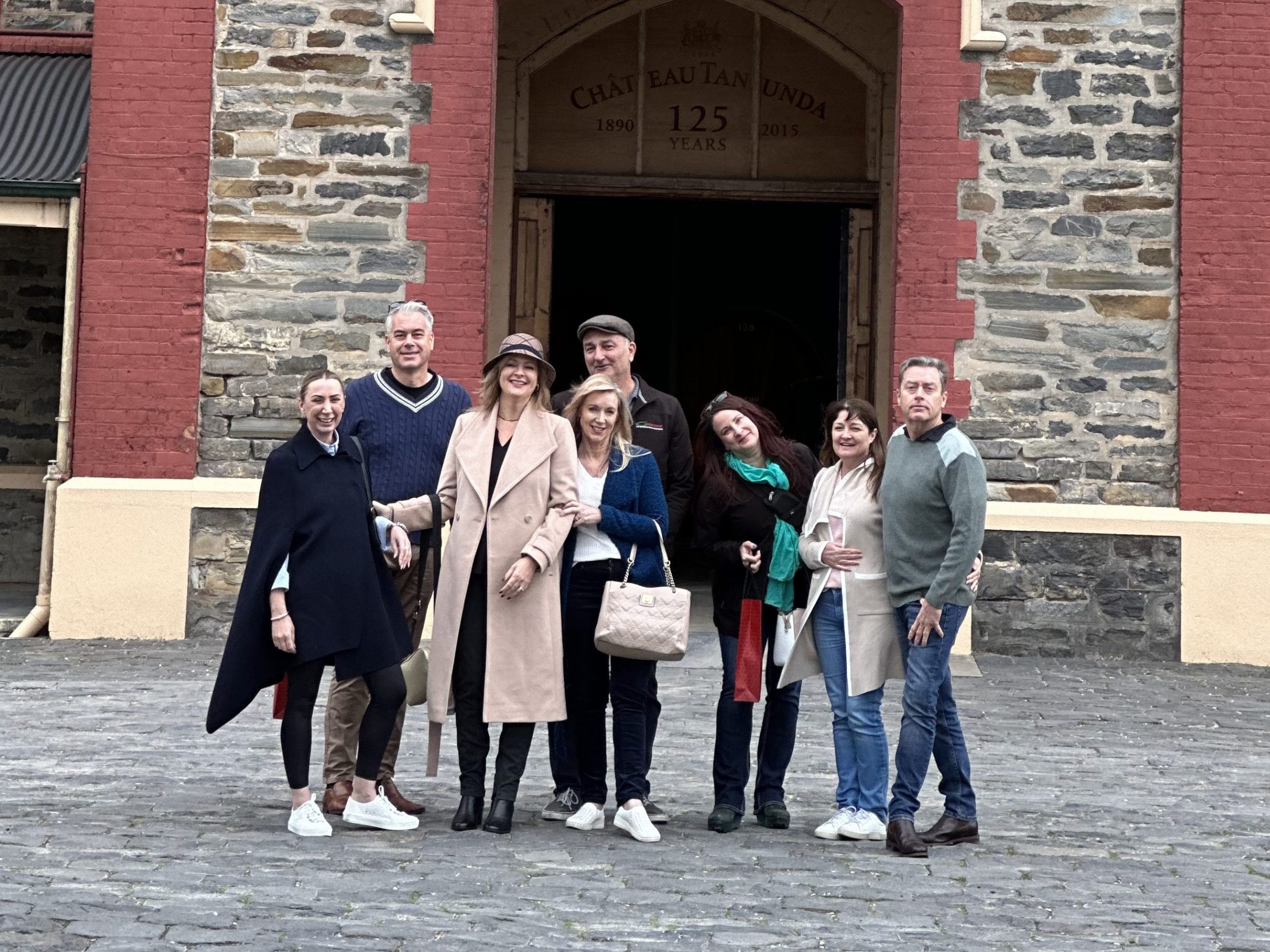 Group of people in front of Chateau Tanunda stone building with red trim.