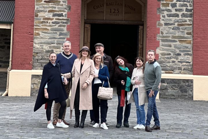 Group of people in front of Chateau Tanunda stone building with red trim.